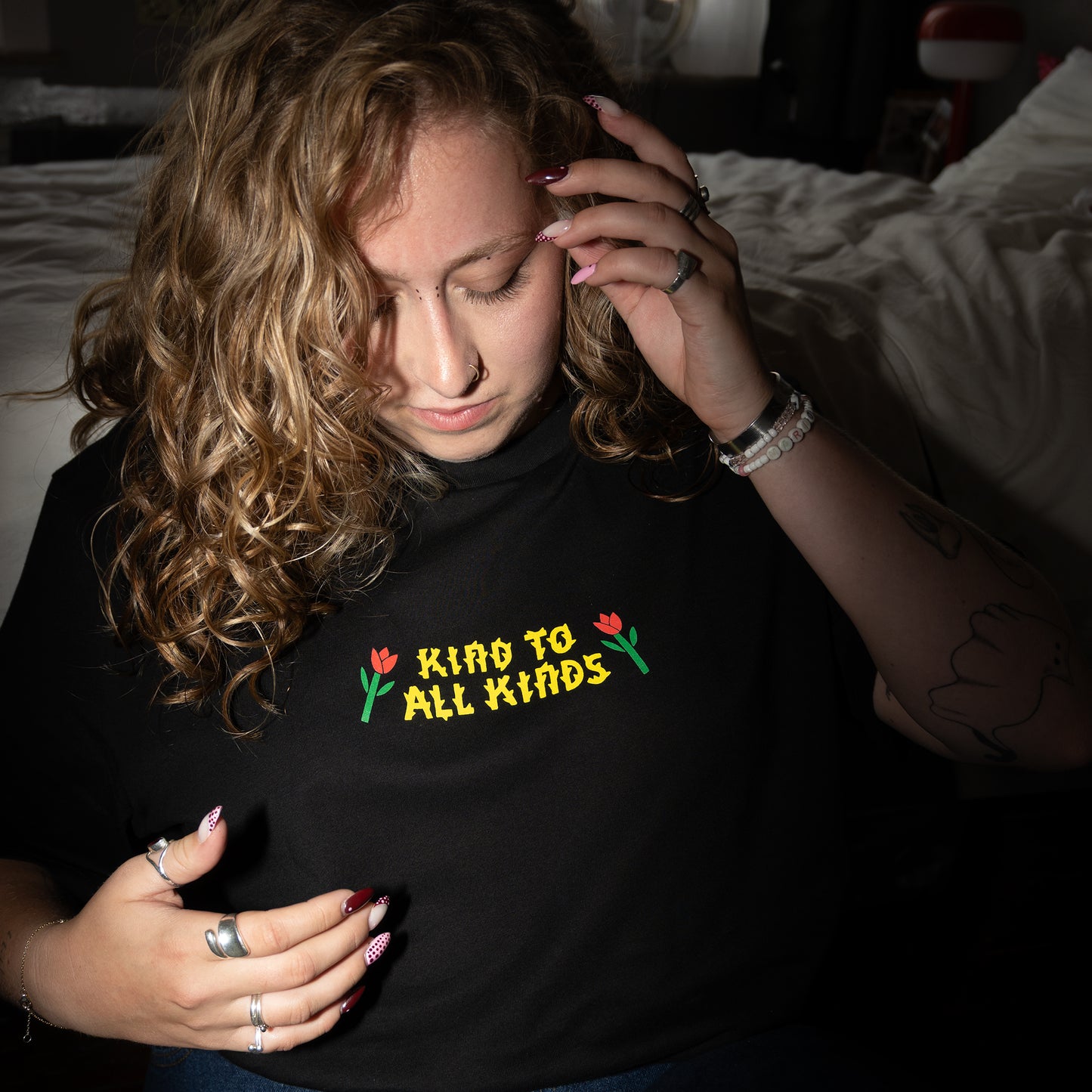Person wearing a black vegan activism t-shirt with 'Kind to All Kinds' text and flowers.